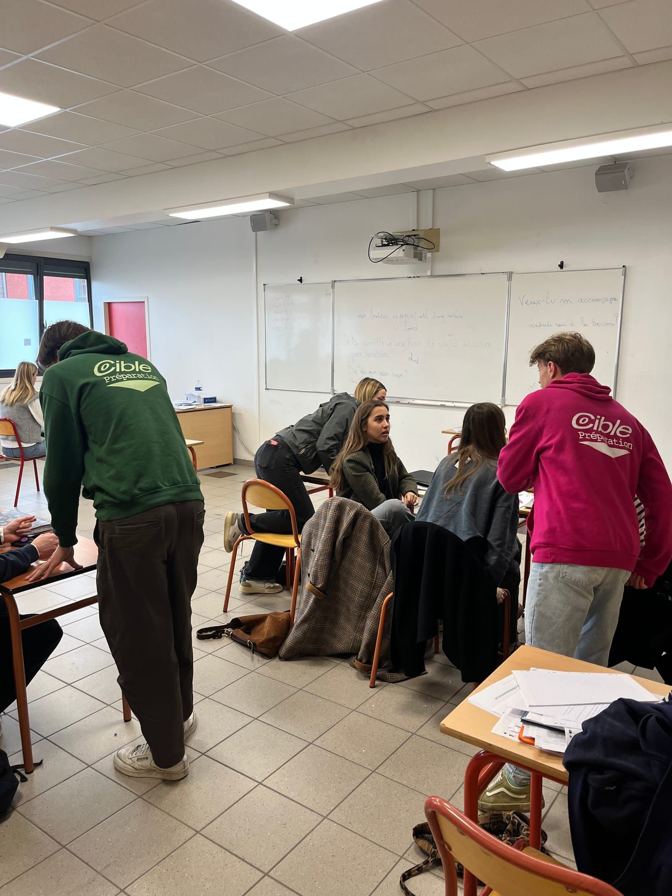 Cibleurs en sweats vert et rose qui aident des élèves pendant un exercice