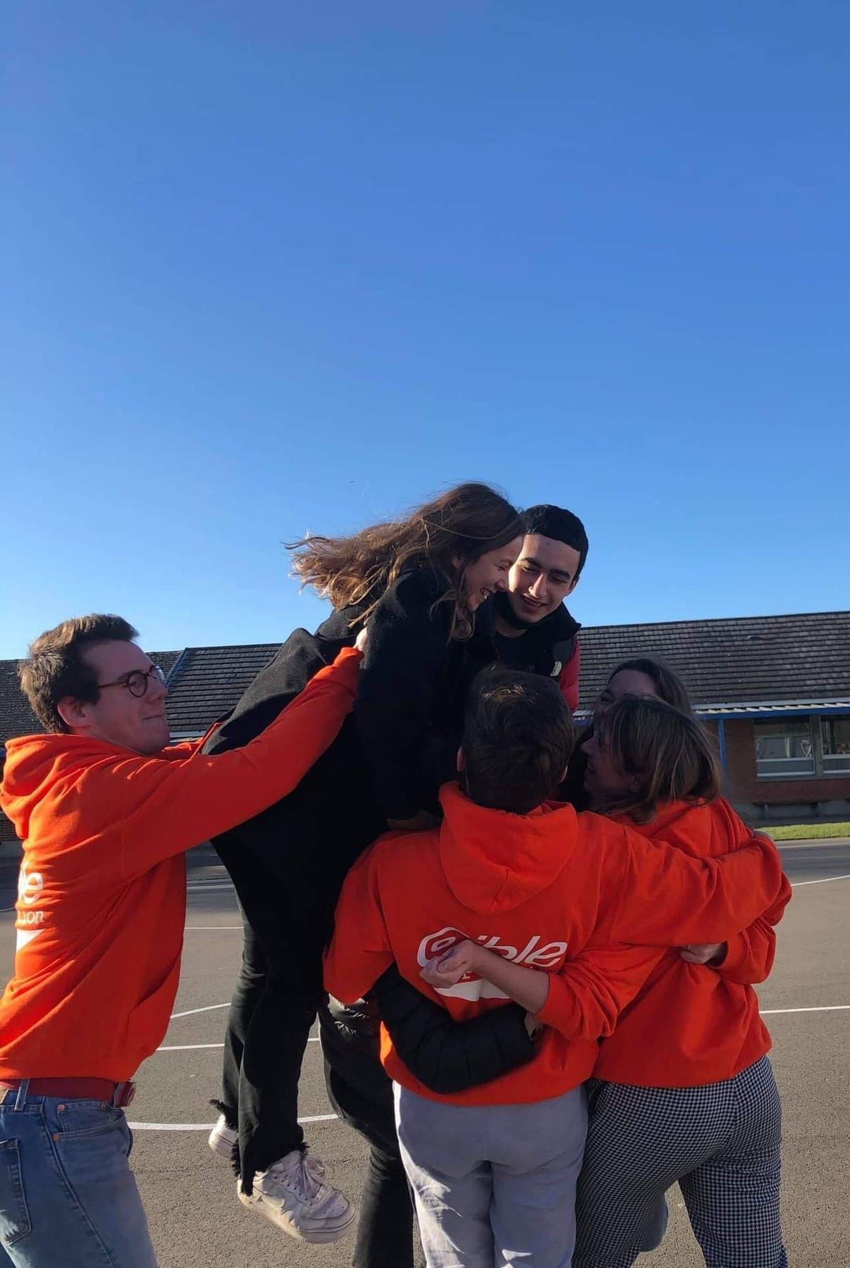 Cibleurs en sweats orange de l’association qui se prennent dans les bras