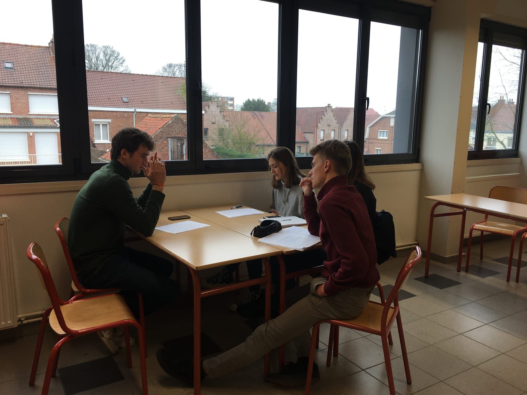 Cours en petit groupe près d’une fenêtre, élèves et cibleur autour des tables